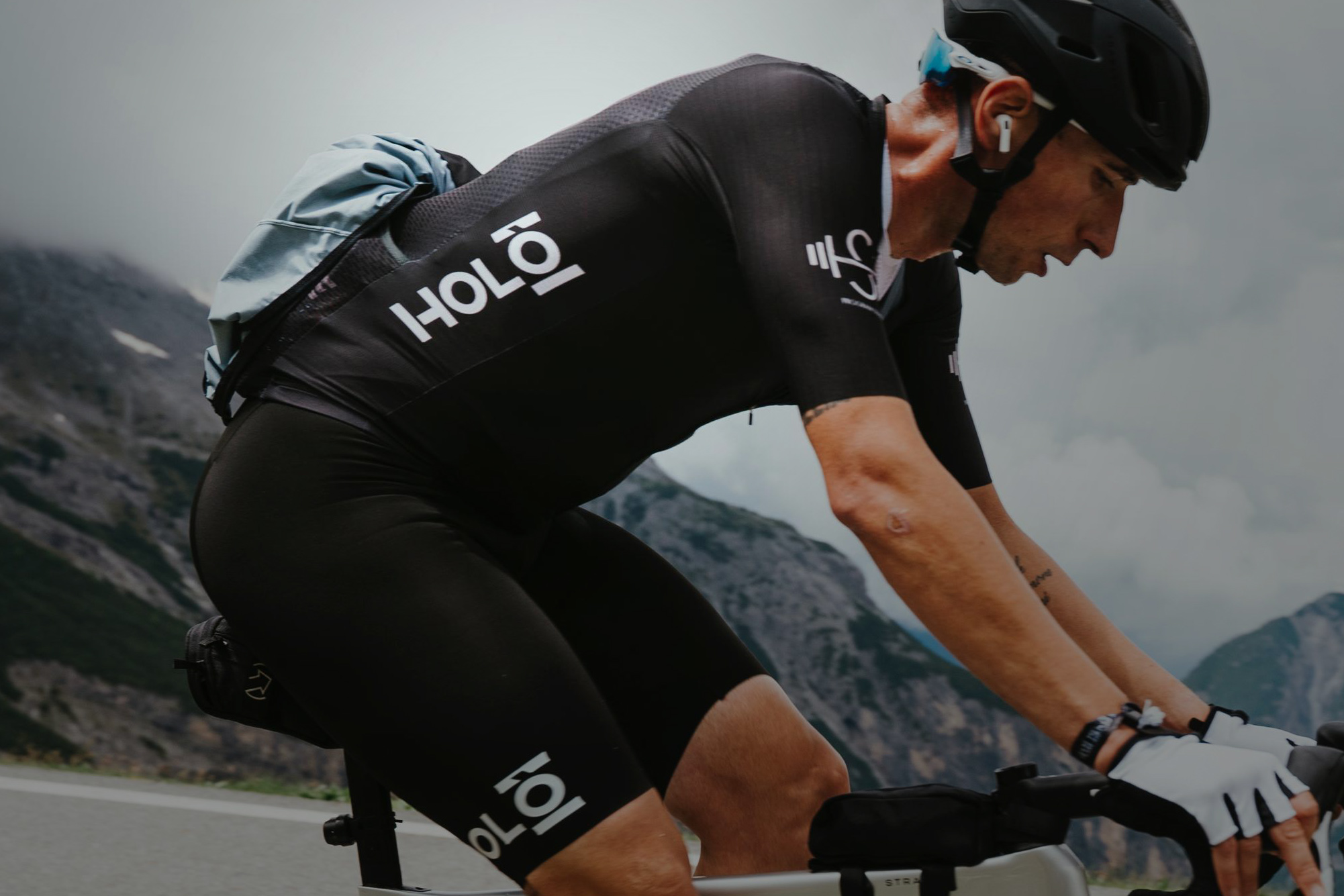 Ciclista con abbigliamento tecnico nero Holò Cycling durante una salita