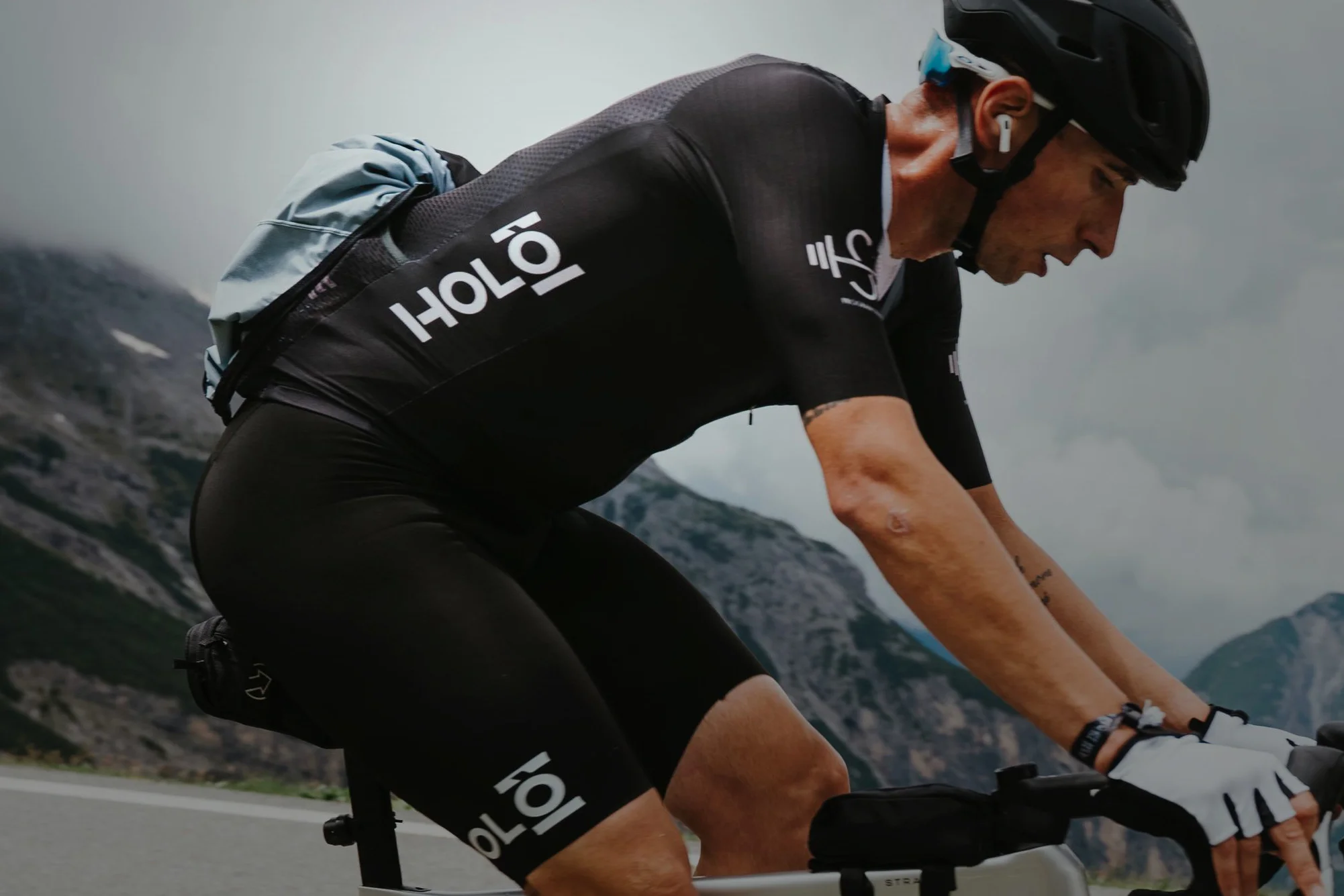Ciclista con abbigliamento tecnico nero Holò Cycling durante una salita